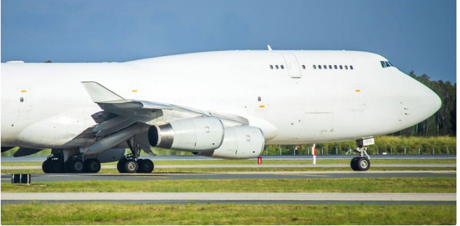 Vue de côté d’un Boeing 747 blanc sur une piste de jour